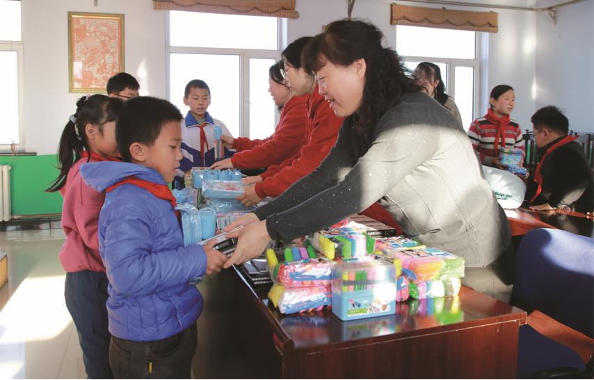 珲春市科海伟业电脑公司工作人员向三家子满族乡小学发放学习用品